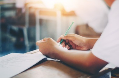 background blur cropped close up  education and school concept students hands with books or textbooks writing to notebooks student's taking exam writing answer in classroom