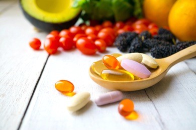 pills and capsules in wooden spoon with fresh fruits.multivitamins and supplement from fruits concept.