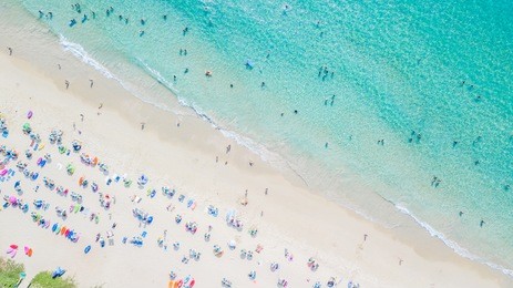 people bathing in the sun, swiming and playing games on the beach. tourists on the sand beach, aerial view of sandy beach with tourists swimming in beautiful clear sea water.
