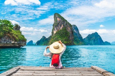 traveler woman with backpack joy relaxing on floating wood bridge and looking beautiful destination island, panyee island, phang nga bay, travel thailand, natural landscape asia, summer vacation trip