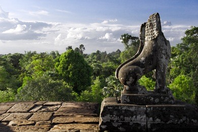 stone lion guardian with forest and sky skyline at pre rup, the east baray, siem reap, cambodia