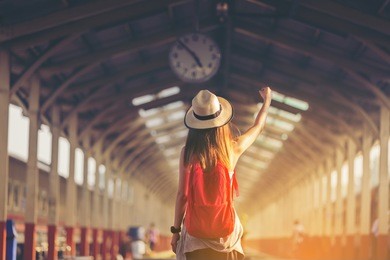 beautiful young asian woman traveler looking clock over head with red bag ,waiting for train at train station, travel and vacation concept.