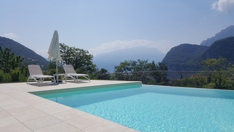 swimming pool with sunbeds and sun umbrella and mountains in the background
