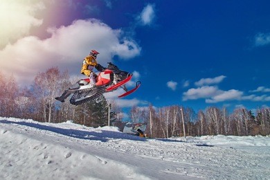 extreme sport race snowmobiles. snowmobile in high jump above track. sportsman on snowmobile. winter competition, sunny day. trick against blue sky. snow motor sports copy space.