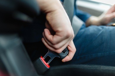 men's hand fastens the seat belt of the car. close your car seat belt while sitting inside the car before driving and take a safe journey. closeup shot of male driver fastens seat belt.