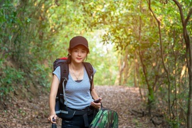 hiker  young women walking in national park with backpack. woman tourist going camping in forest.  travel concept
