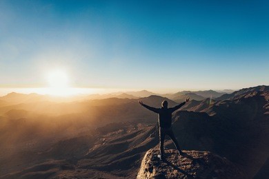 man stands facing the rising sun and meditates on mount sinai in egypt.