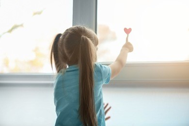 little girl with red heart near window. autism concept