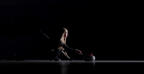 curling player delivering a stone on a curling rink, sliding over the ice, isolated on the black background. curling match curler athlete winter sports women.