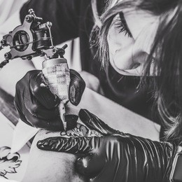 black and white photo of woman tattoo during tattooing process