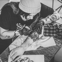 black and white photo of woman tattoo master and man during tattooing process in studio