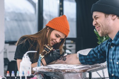 man with grimace of pain during tattooing process in studio