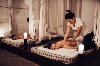 two young women are relaxing in spa and wellness center while receiving body massage. beauty treatment concept.
