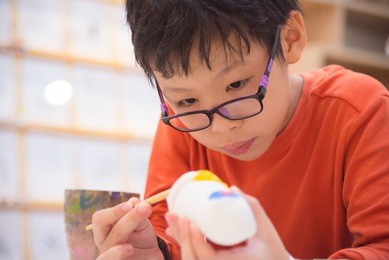 young asian boy painting craft by color brush in classroom at school
