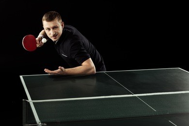 focused tennis player playing table tennis isolated on black