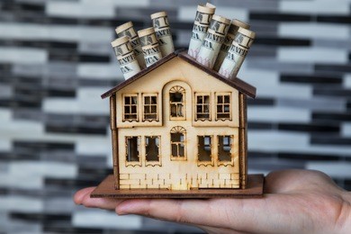 real estate and mortgage investment. being an easy way homeowner. the woman holds house and dollars.