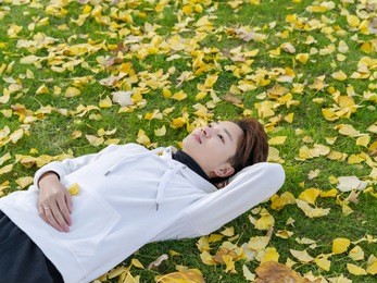 young chinese smiling man portrait laying in foliage in autumn park. outdoor.