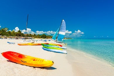 colorful kayaks and sailing boats on a tropical beach in cuba