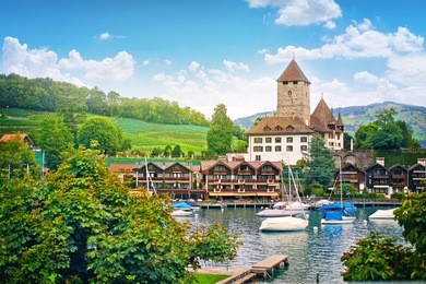 panorama of the landscape with a lake and an old historical castle in the beautiful spa town of spiez, switzerland, europe