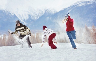 group of three happy friends having fun playing snowballs. winter holidays concept