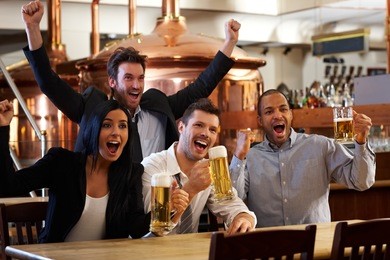 happy friends in pub watching sport in tv together drinking beer cheering for team and celebrating.