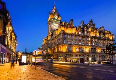 streets of edinburgh, scotland, at night with light trails of street traffic on princes street.