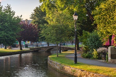 the river windrush flows under the famous stone bridge in the cotswolds village of bourton-on-the-water, gloucestershire, england