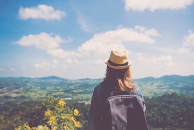 young asian woman standing alone outdoor with wild forest mountains on background travel lifestyle and survival concept rear view