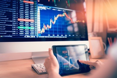 businesswoman trading stocks with tablet and graph analysis in desktop computer