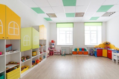 spacious bright game room in the kindergarten with toys, two large windows and tables for classes. natural light.