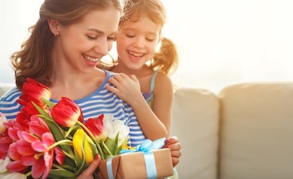 happy mother's day! child daughter congratulates mother and gives a bouquet of flowers to tulips and gift
