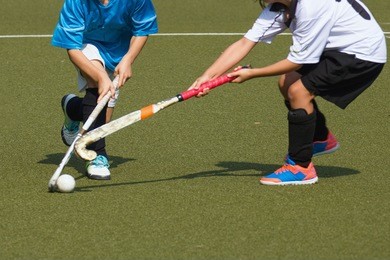 two child field hockey players. attacker in blue jersey dekes defender in white and gets past her or him