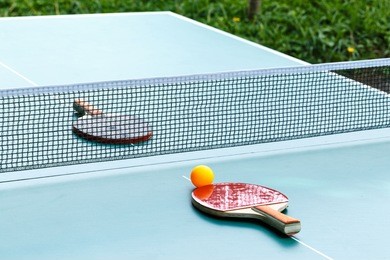 table tennis ball and paddle on green table

