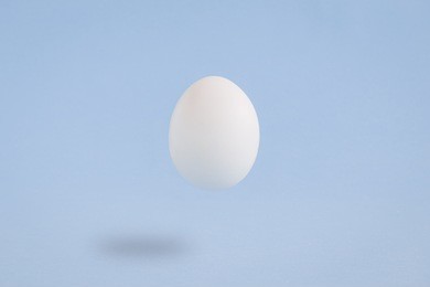 white egg on plain pastel blue background. minimal concept.