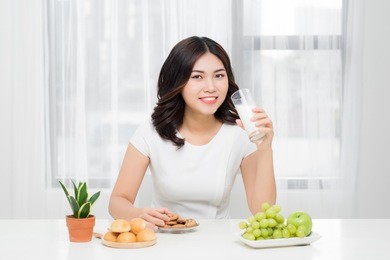 healthy woman is drinking milk from a glass isolated on white background.