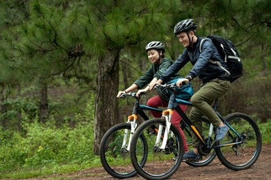 side view of young asian couple wearing helmets while practicing cross-country cycling