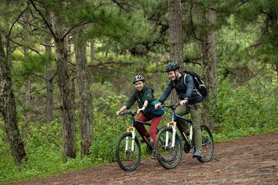 young asian couple enjoying cross-country cycling through woodland