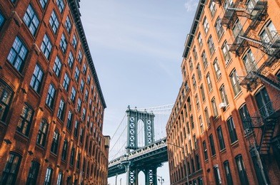manhattan bridge seen from a red brick buildings in brooklyn street in perspective, new york, usa