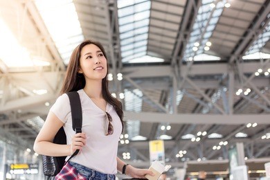 portrait charming beautiful woman. gorgeous girl is going to foreign country or oversea by herself. attractive traveler woman looks nervous, excited. pretty asian girl stands at airport. copy space