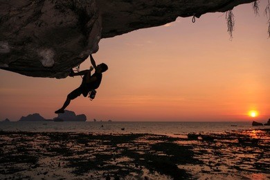 beautiful sunset with shadow of unidentify thai climber climbing on foreground at the  over hang cliff in tonsai, railay beach  krabi province, southern of thailand   