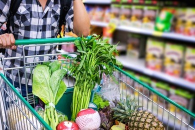 man with shopping cart purchasing food in a supermarket. closeup detail of shopping cart.