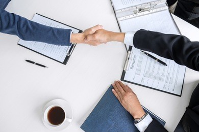 greeting new colleagues, handshake while job interviewing, male candidate shaking hands with interviewer or employer after a job interview, employment and recruitment concept.