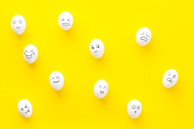 emotions in communication at social media. faces drawn on eggs. yellow background top view