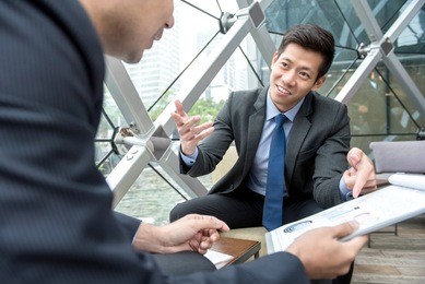 young asian businessman discussing financial statistic charts with his partner at office lounge
