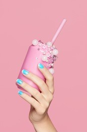 blue nails. woman with soda can in hands on pink background. close up of female hands with bright blue manicure holding pink soda can with beads. nails design. high quality image.
