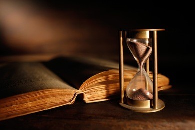 old hourglass with open ancient book
