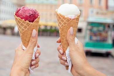 two colorful tasty ice cream cones in hands
