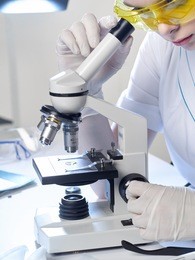 medical worker women in blue gloves working with microscope in white light and a medical laboratory.