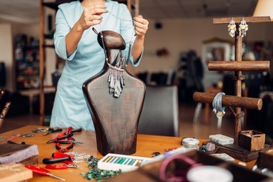 female person trying on necklace on mannequin