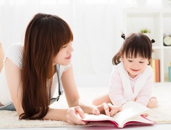 happy mother reading book to daughter
